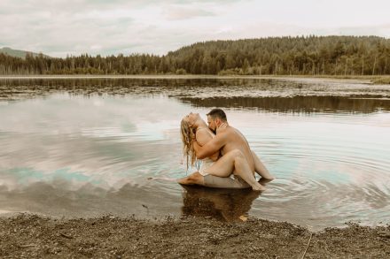 Playful couple takes a spontaneous dip in the lake, candid engagement shoot