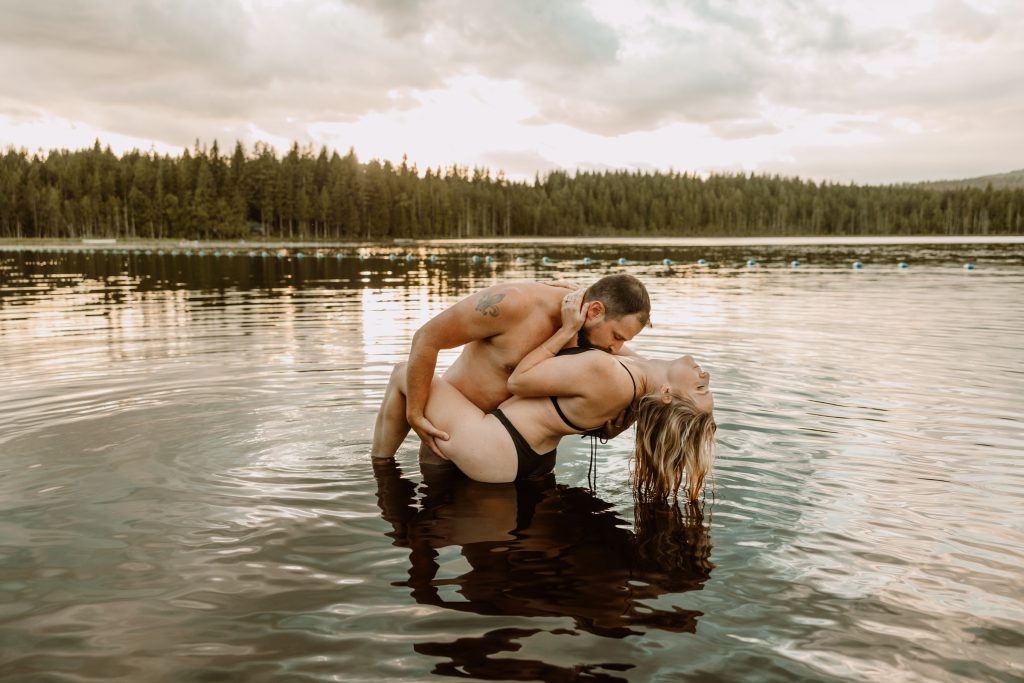 Playful couple takes a spontaneous dip in the lake, candid engagement shoot