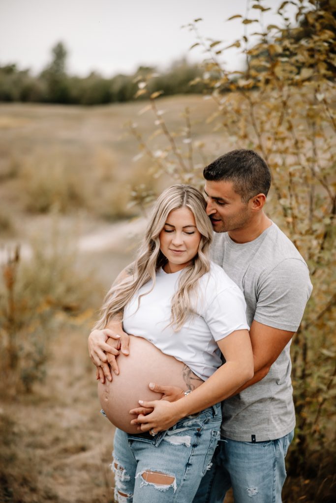 A radiant pregnant woman walks gracefully in a sun-drenched field