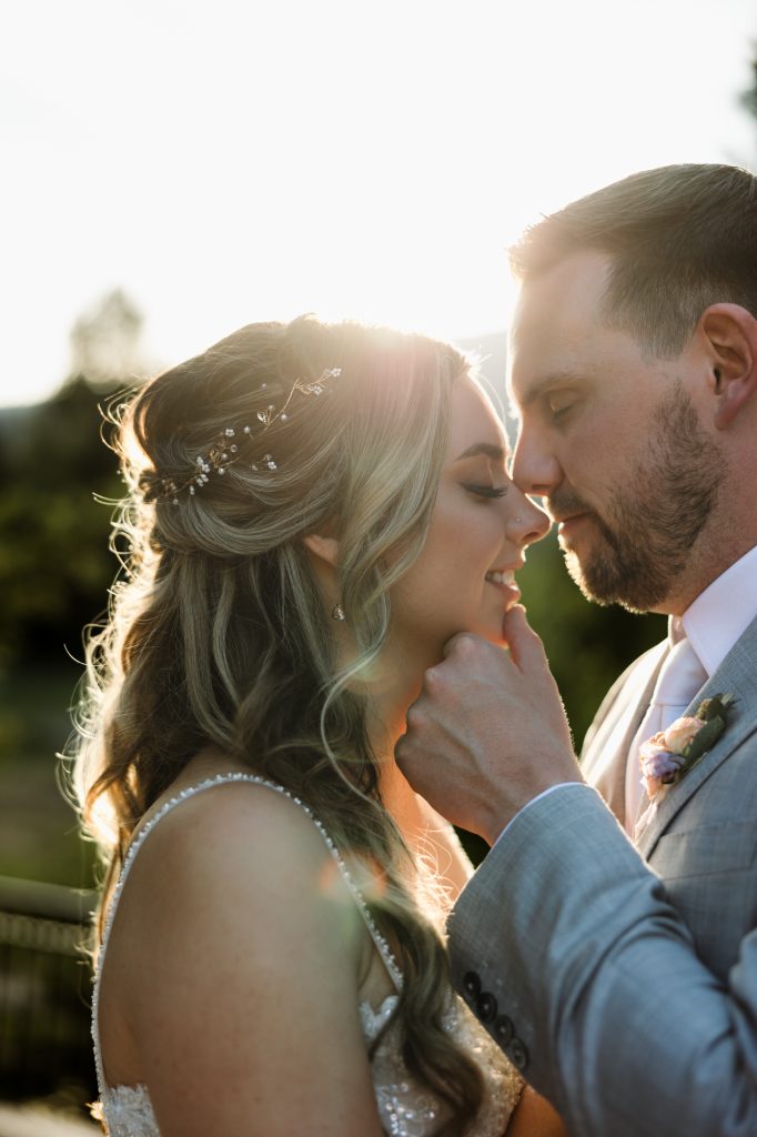 A bride and groom lean in close in warm evening light