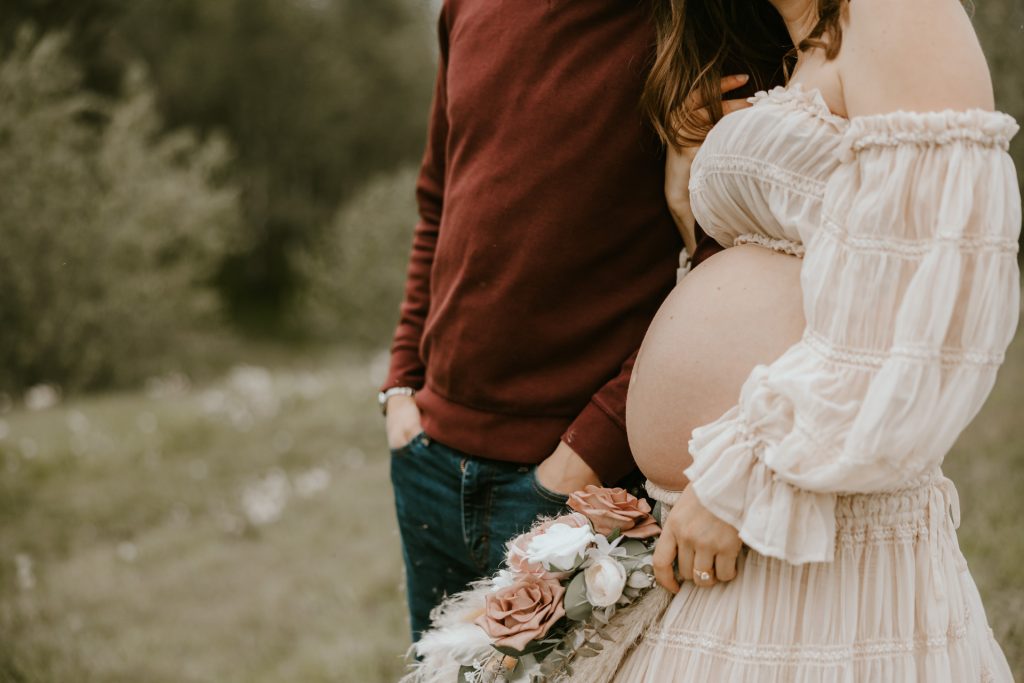 Expectant mother in a flowing dress standing in a lush Fraser Valley meadow during a maternity photoshoot.