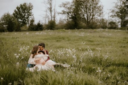 Mother-to-be cradling her baby bump in a serene meadow setting in Fraser Valley, surrounded by nature.