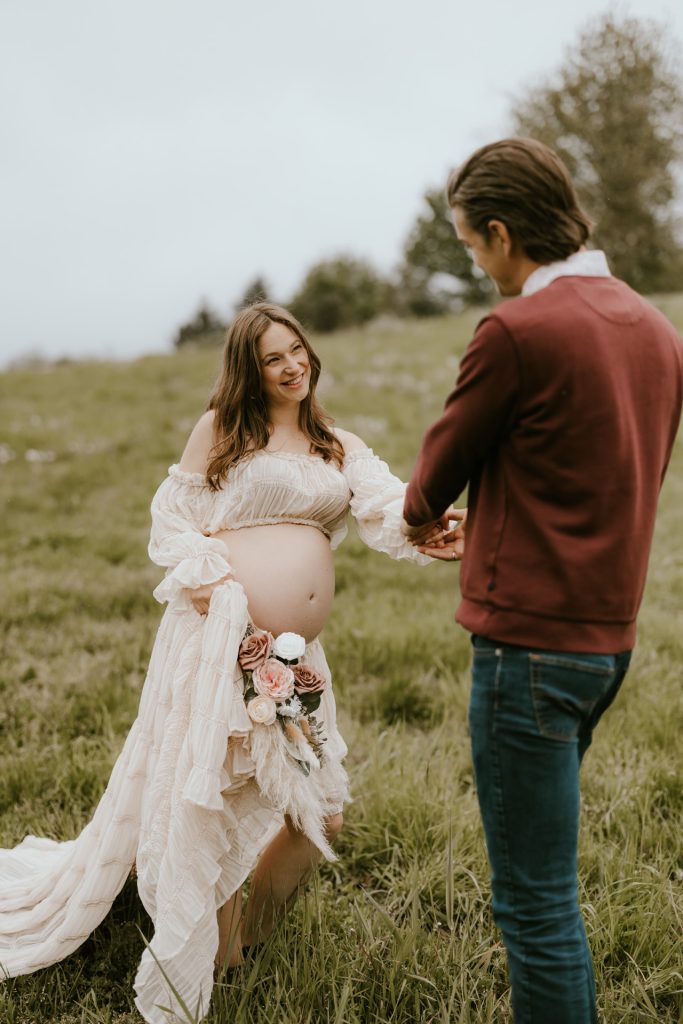 Mother-to-be cradling her baby bump in a serene meadow setting in Fraser Valley, surrounded by nature.