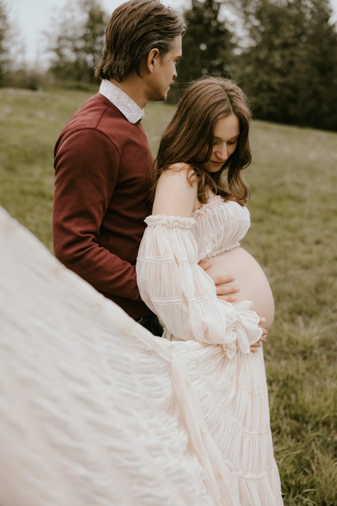Glowing pregnant woman in a picturesque Fraser Valley meadow, highlighting the beauty of pregnancy in nature.