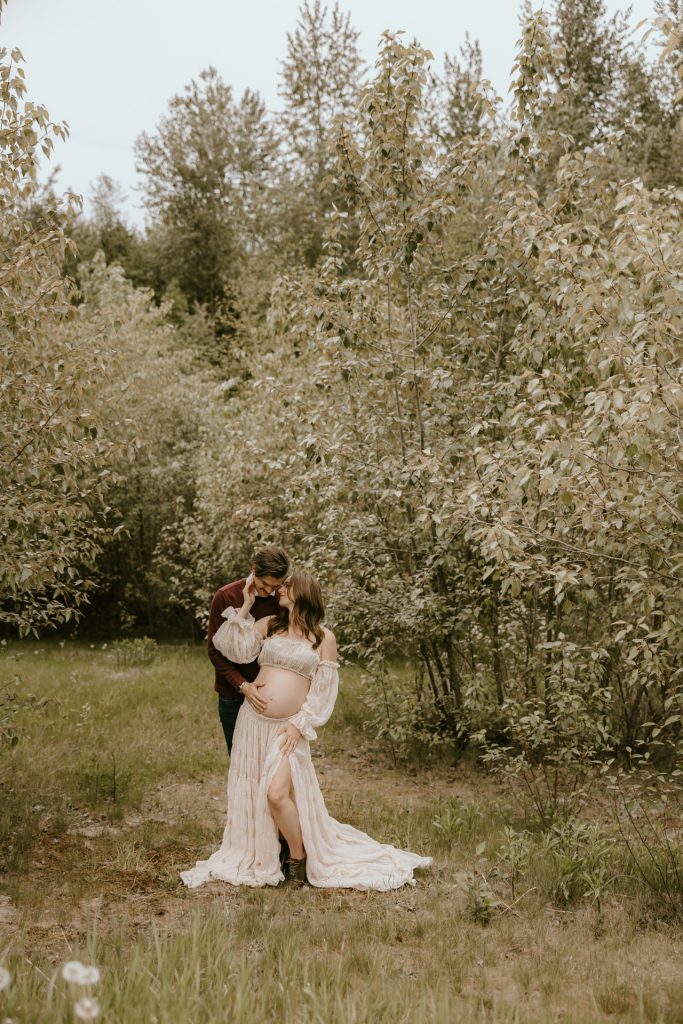 Expectant mother in a flowing dress standing in a lush Fraser Valley meadow during a maternity photoshoot.