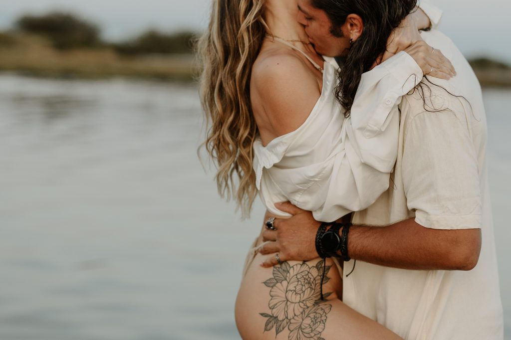 Passionate couple kissing in waist-deep water during sunset session at Vancouver's Mud Bay