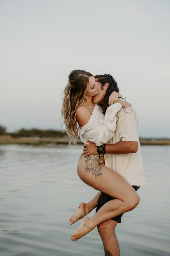 Couple in love holding each other with water rippling around them at romantic Mud Bay location