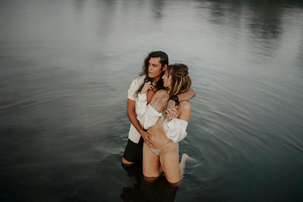 Bikini photoshoot with couple laughing and playing in the ocean at Mud Bay coastal setting