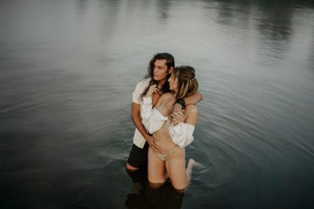 Bikini photoshoot with couple laughing and playing in the ocean at Mud Bay coastal setting