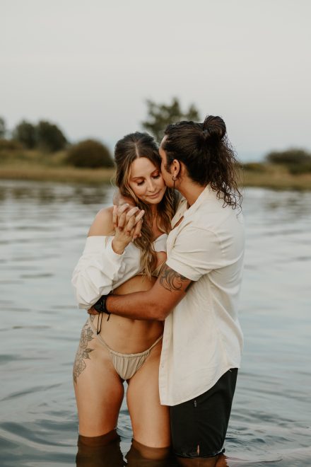 Water embrace between couple in swimwear at a secluded beach location in British Columbia