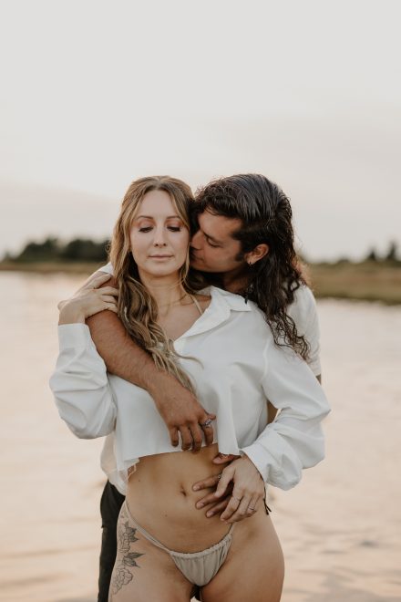 Romantic couple snuggling in shallow ocean water at Mud Bay, Vancouver BC during golden hour