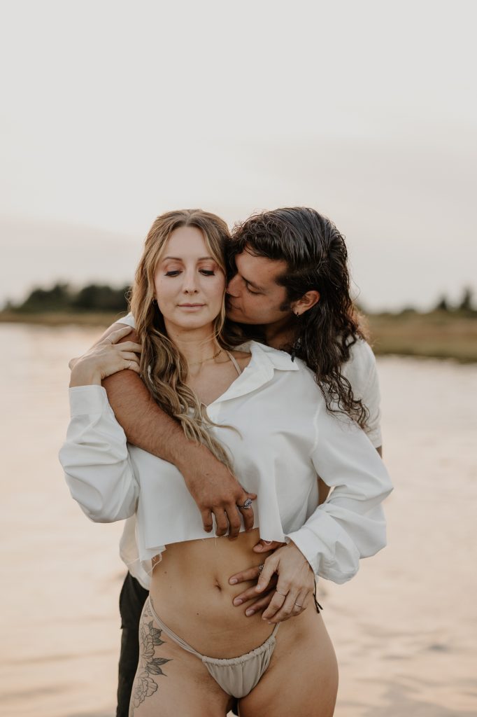 Romantic couple snuggling in shallow ocean water at Mud Bay, Vancouver BC during golden hour