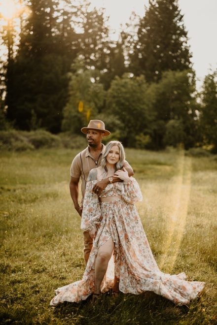 Intimate portrait of parents holding each other with gentle smiles in tall grass
