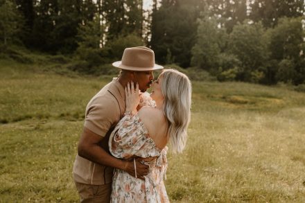 Sweet moment of couple gazing at each other with meadow backdrop