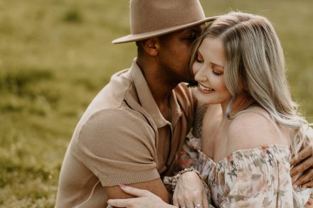 Golden hour photo of parents cuddled together in open field setting