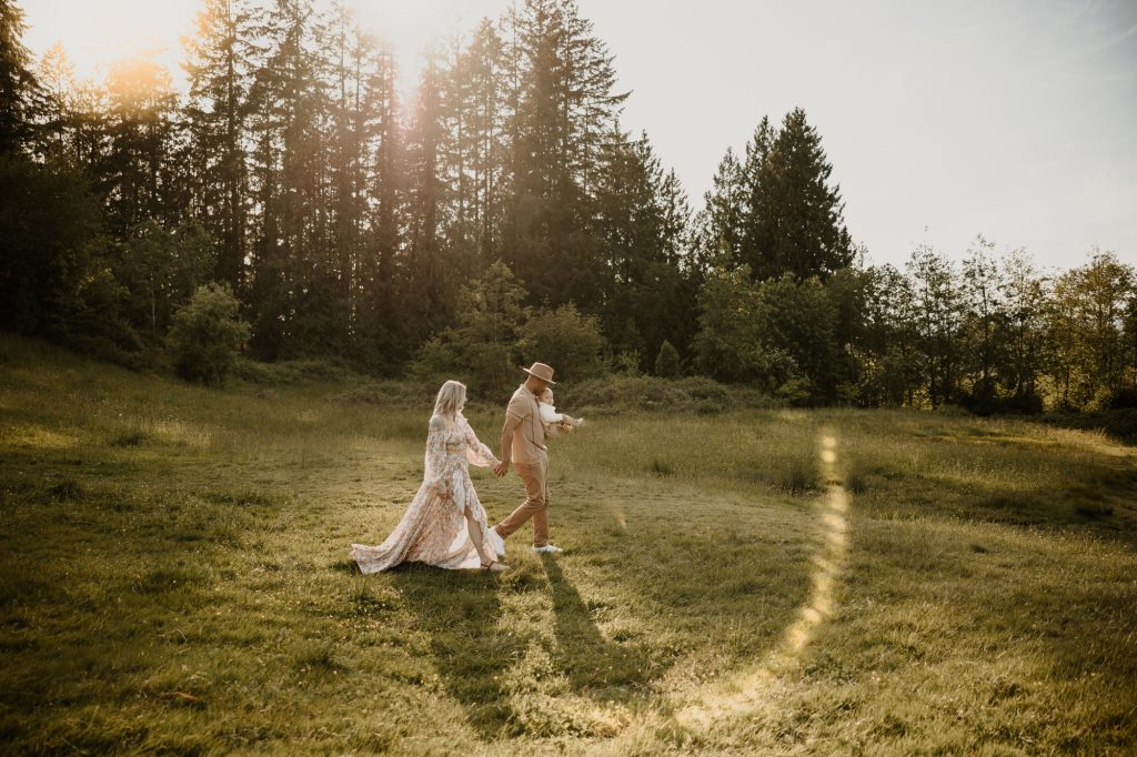 Family of three walking through a glowing meadow holding hands