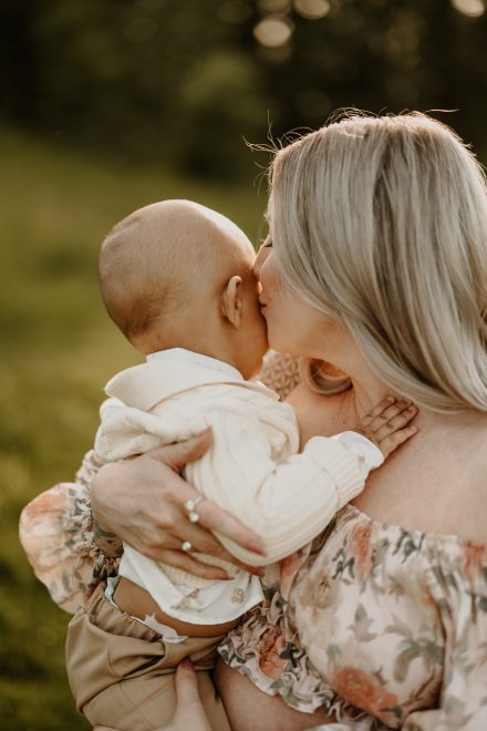 Candid family moment with baby reaching for parents' faces in warm sunlight