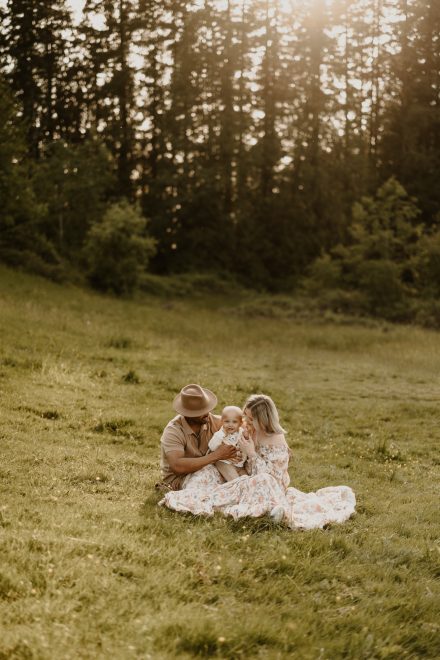 Family sitting together on a blanket in the meadow during golden hour