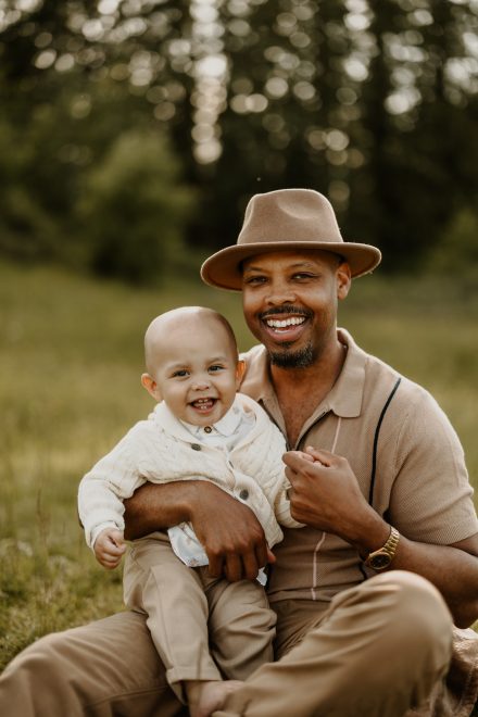 Dad cuddling baby boy in the meadow of maple ridge