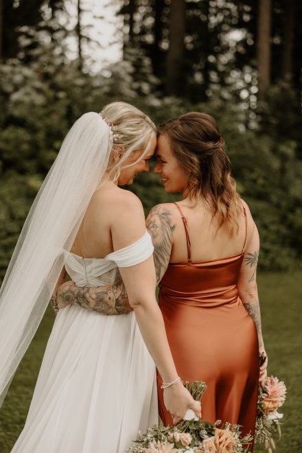 Bridesmaids laughing and holding bouquets in elegant mismatched dresses