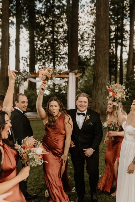 Fun bridal party dancing together across riverside lawn at Rowena’s venue