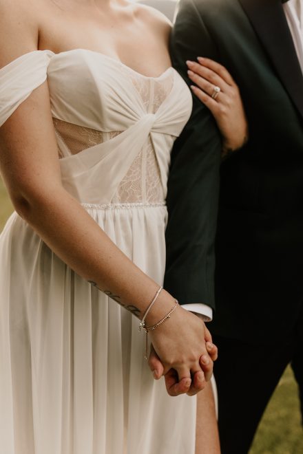 Bride and groom holding hands with details of the wedding dress