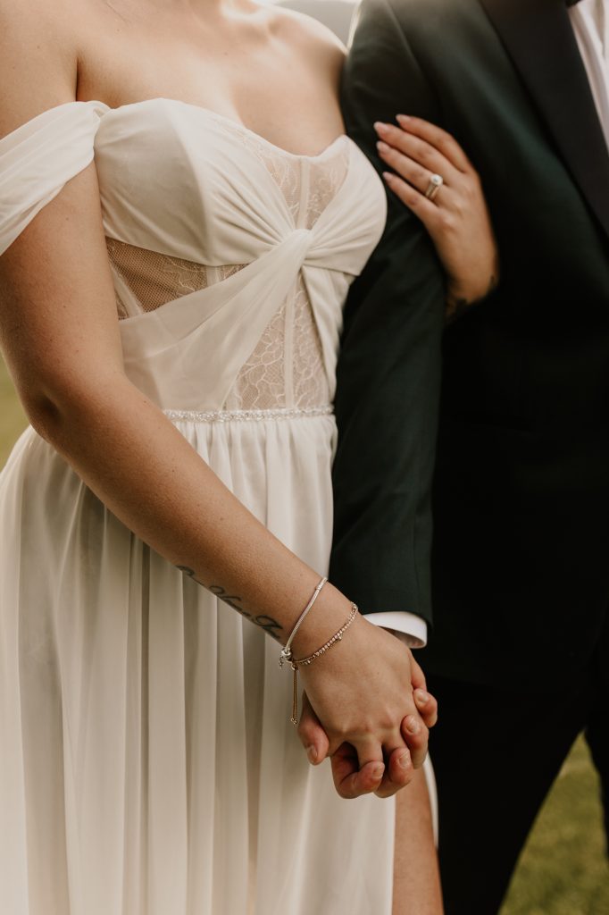 Bride and groom holding hands with details of the wedding dress