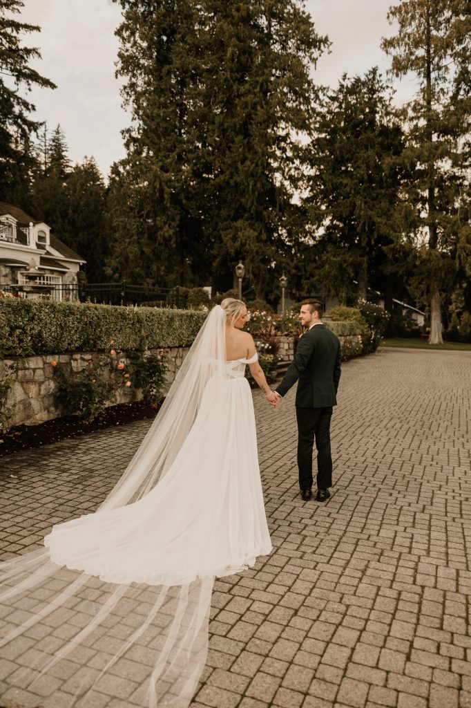 Bride looking over shoulder with train flowing behind her in Fraser Valley setting