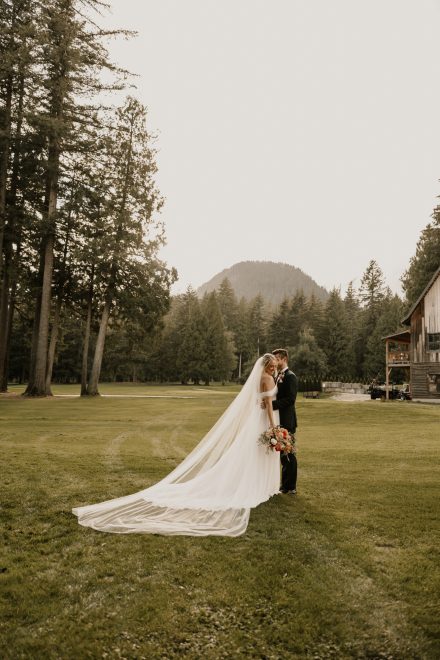 Bride and groom holding each other along the riverbank with soft sunset light