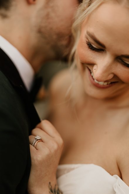 Laughing candid of bride and groom walking hand-in-hand on riverside path