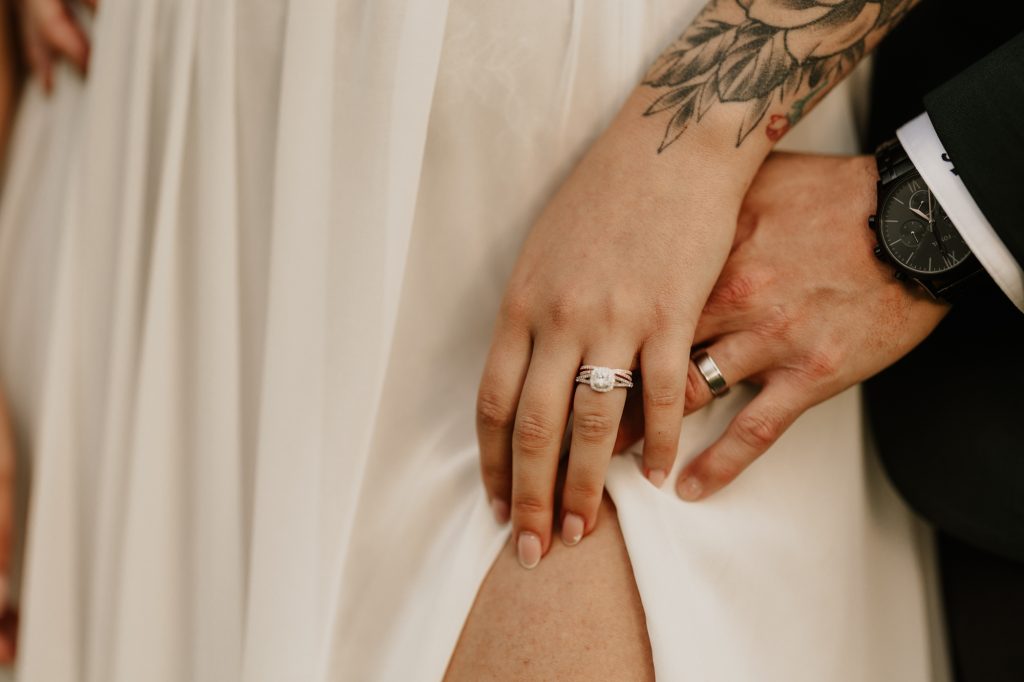 Elegant close-up of couple’s hands intertwined with wedding bands visible