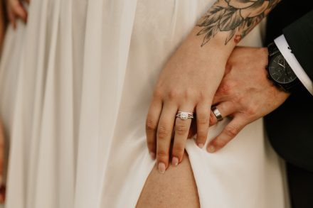 Elegant close-up of couple’s hands intertwined with wedding bands visible