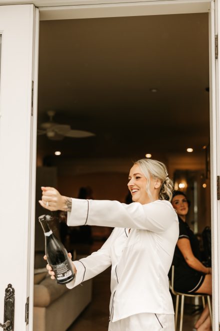 Bride popping champagne when the sun started shining through the rain clouds