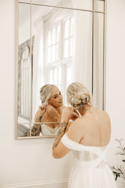 Bride putting her earrings on before walking down the ailse