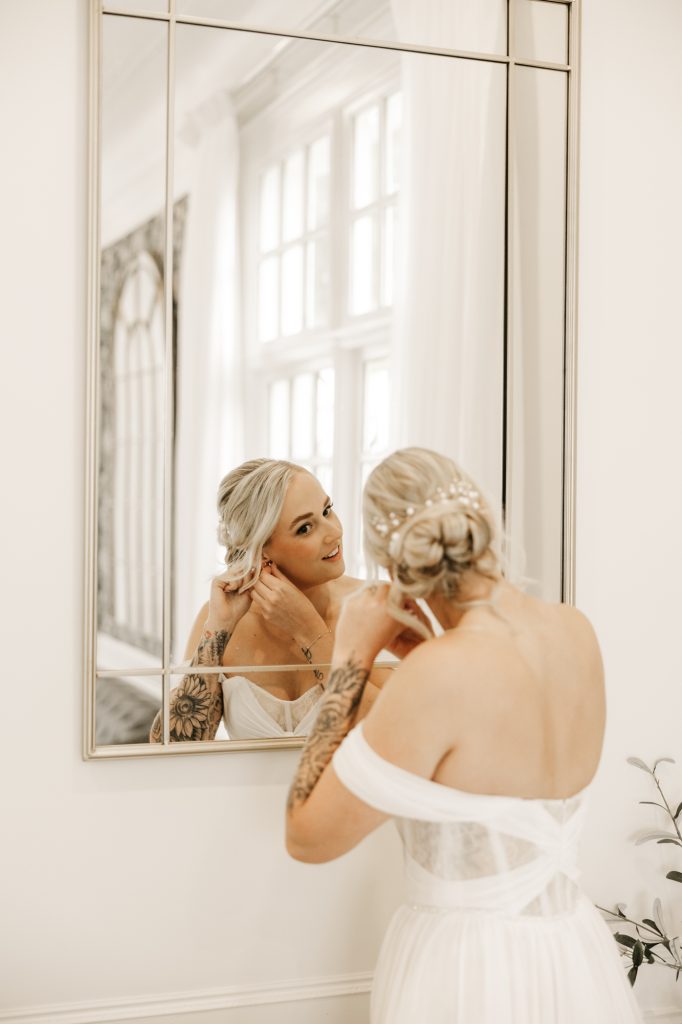 Bride putting her earrings on before walking down the ailse