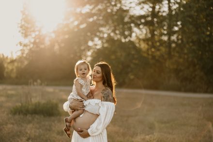 Candid maternity photo with woman laughing in field of tall grasses, Blackie Spit Vancouver