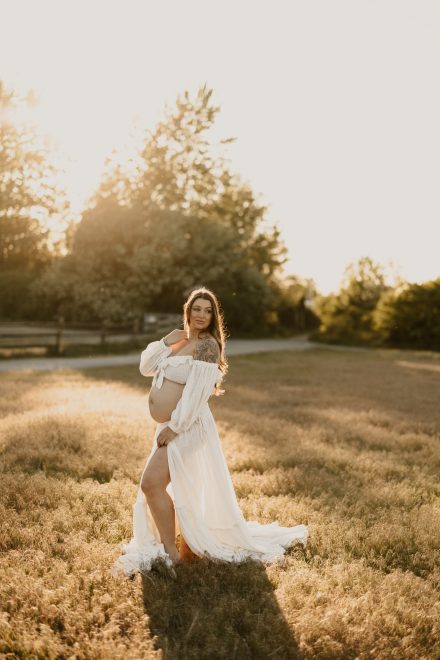 Mother-to-be radiating joy in meadow filled with sunlight and soft grass textures in Vancouver