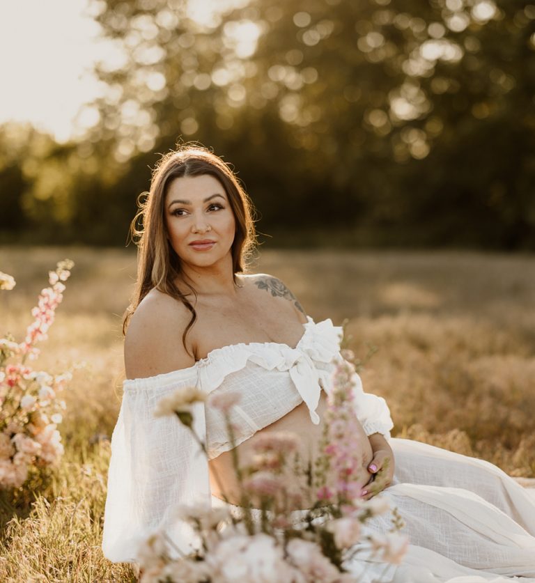 Glowing mother-to-be in flowing maternity dress standing in golden meadow at Blackie Spit Vancouver