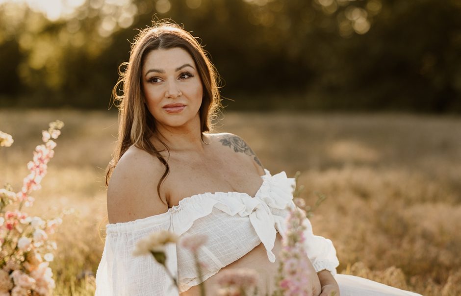 Glowing mother-to-be in flowing maternity dress standing in golden meadow at Blackie Spit Vancouver