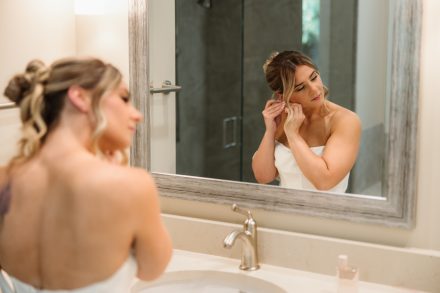 Melissa putting in her earrings during bridal prep at her family backyard wedding in Abbotsford