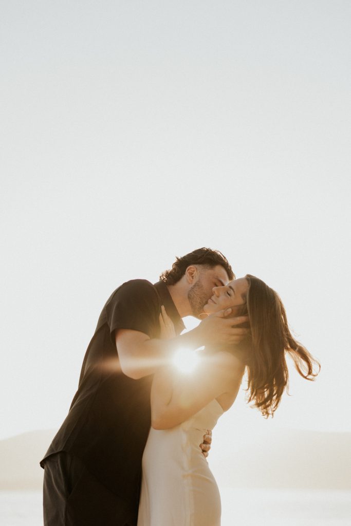 A couple kiss as the sun flares between them
