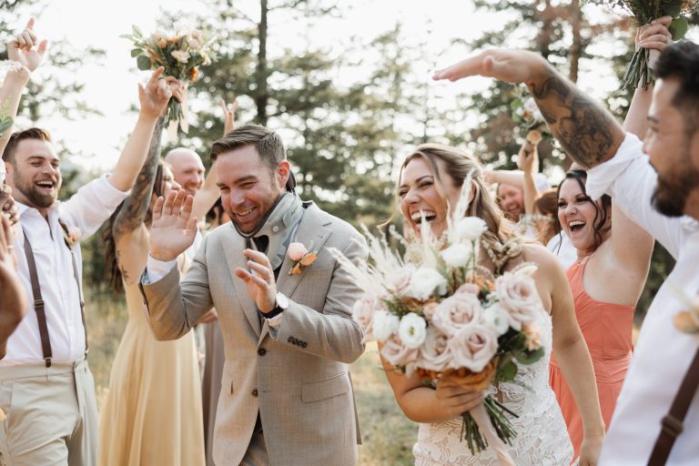 A wedding party cheers around the couple outdoors